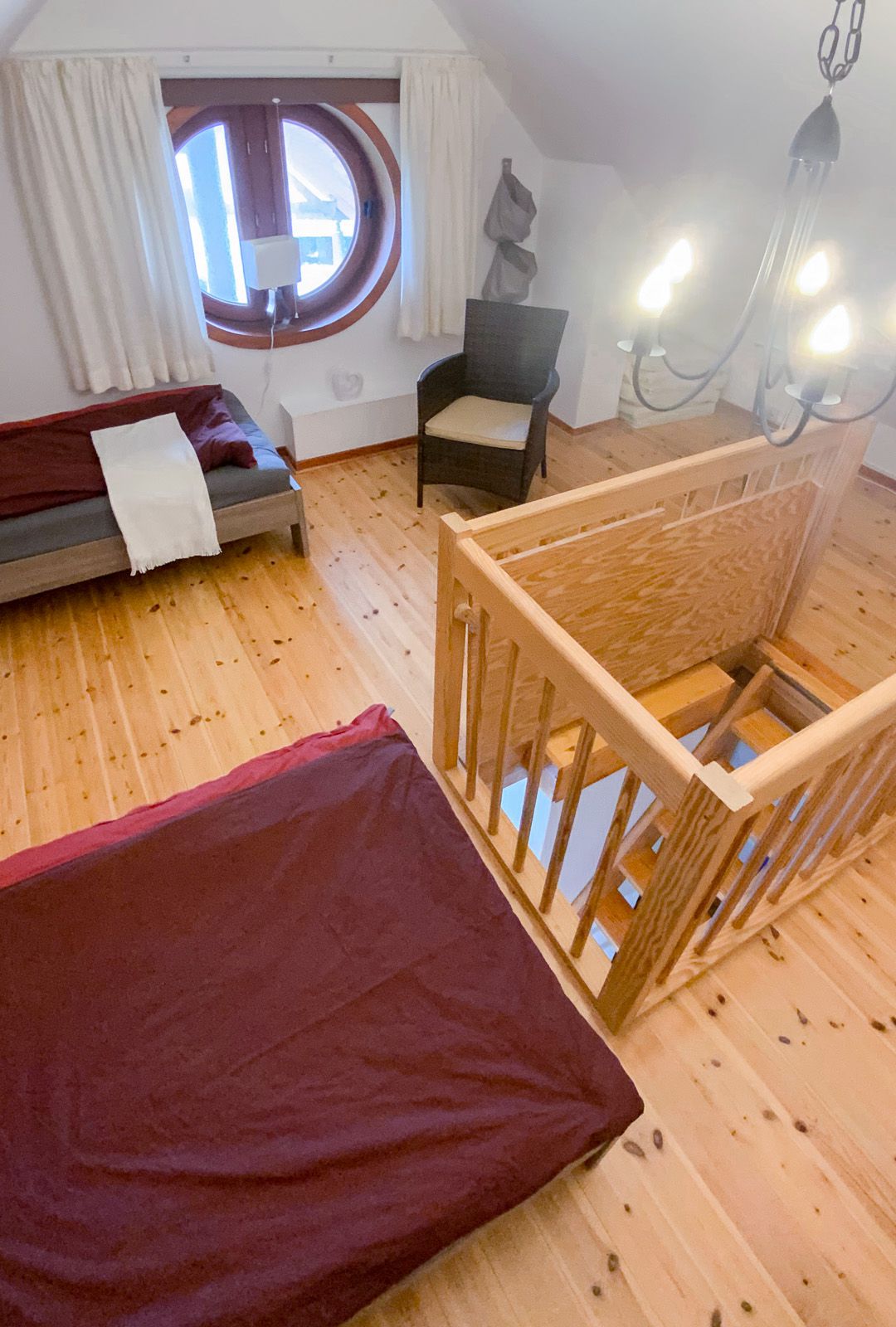 Schlafbereich im Dachgeschoss mit zwei Einzelbetten & rundem Fenster und Stuhl