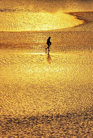 Person im Watt bei Sonnenuntergangslicht